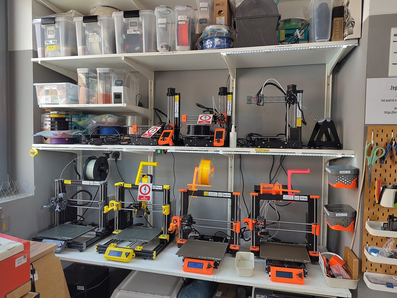 Echtes Foto: mehrere 3D-Drucker nebeneinander in Regalen im Hackerspace Wrocław