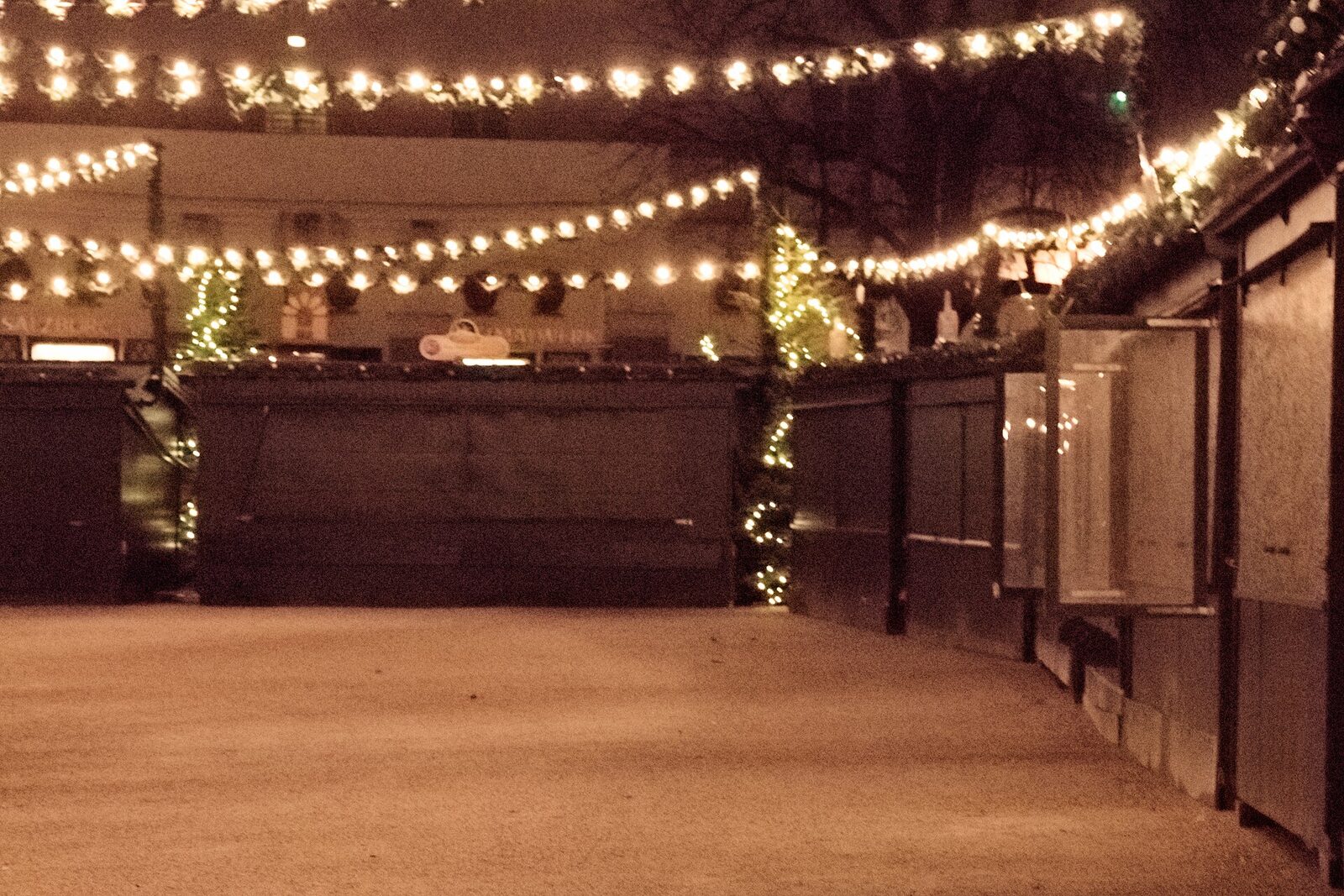 Echtes Foto: Stände des Christkindlmarkts in der Salzburger Altstadt am Abend, mit Lichterketten